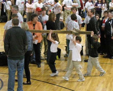 Kindergarten students carry in the cross